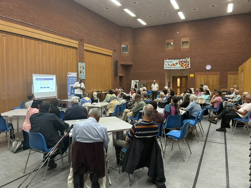 A large community hall session with residents attending a digital training talk
